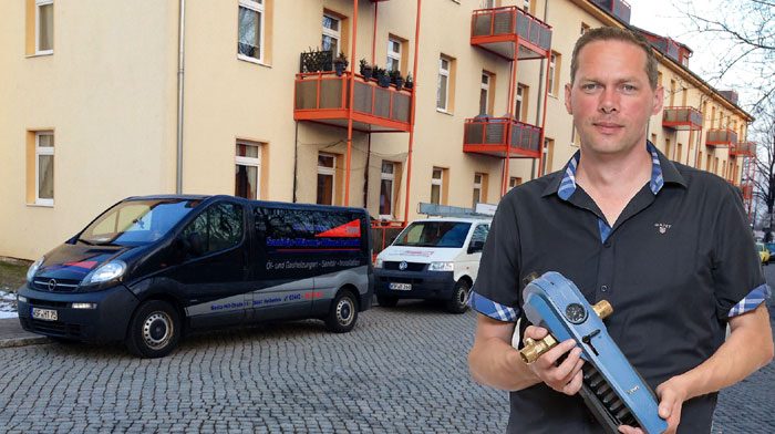 Monteur von SWK mit Werkzeug vor den beschrifteten Firmenwagen